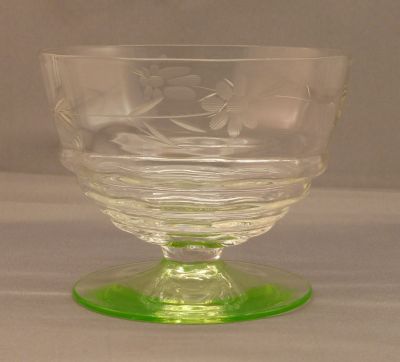 Engraved dessert bowl with uranium foot
Vertical optic rib pattern to bowls and horizontal ribbing at base. Heat finished rims. Likely English. Lead crystal ring. 4 in. diameter, 3 in tall. 
Keywords: blown;table;sold;dessert;engraved